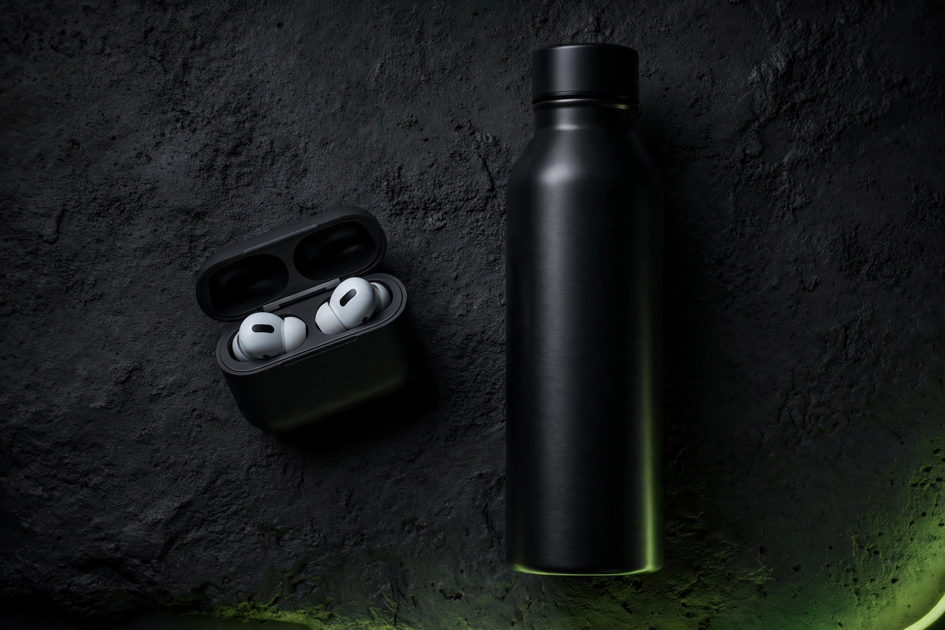 Insulated water bottle and wireless earbuds arranged in a flat lay